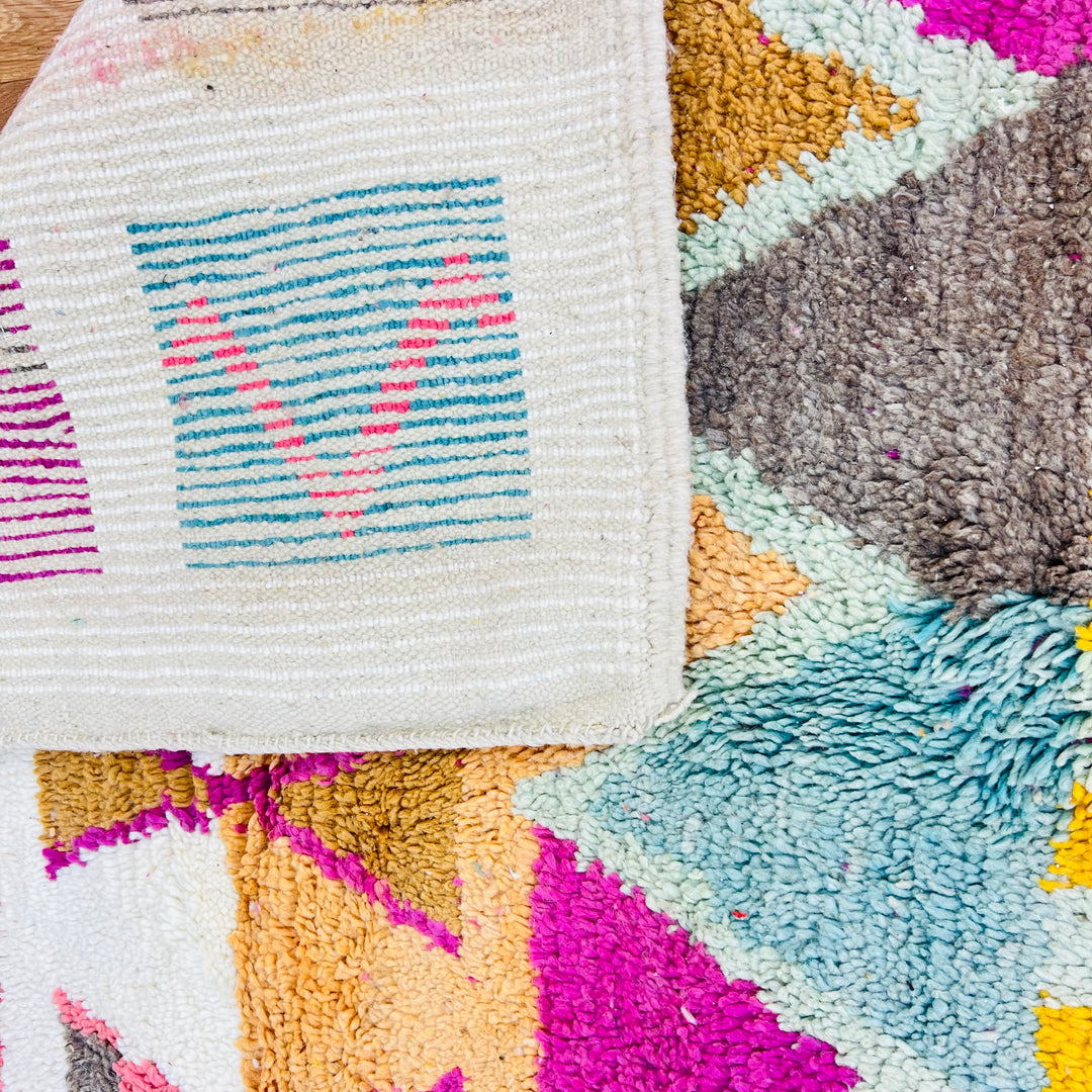 Colorful vintage Moroccan rug with geometric patterns in pink, turquoise, orange, and yellow. Handmade Berber wool rug.