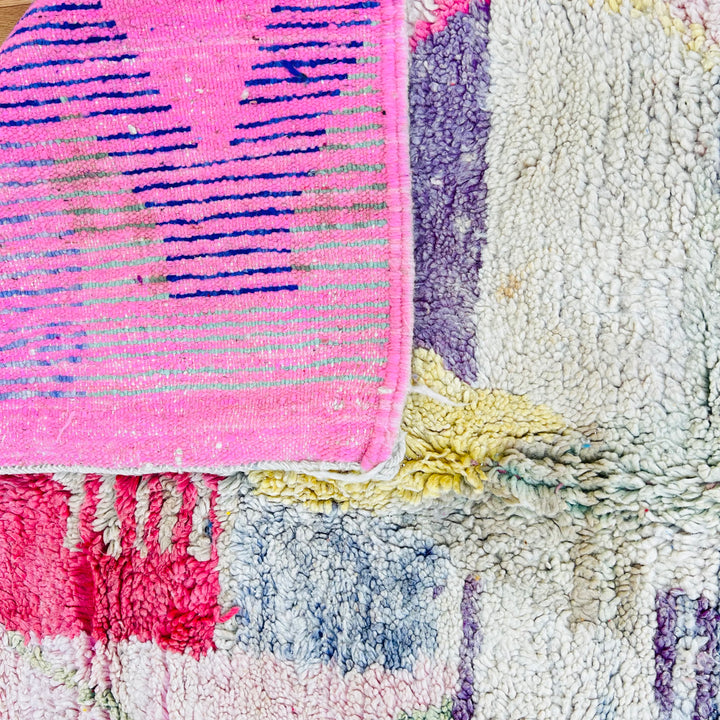 Close-up of vintage Moroccan rug showing colorful tribal motifs and soft wool texture.