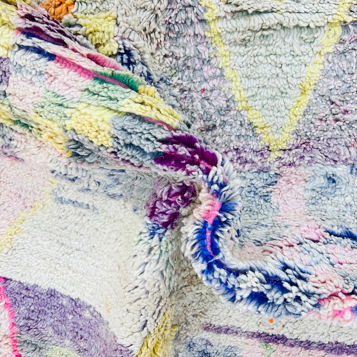 Colorful vintage Moroccan wool rug with abstract tribal motifs and geometric symbols in purple, yellow, grey, pink, and red hues.