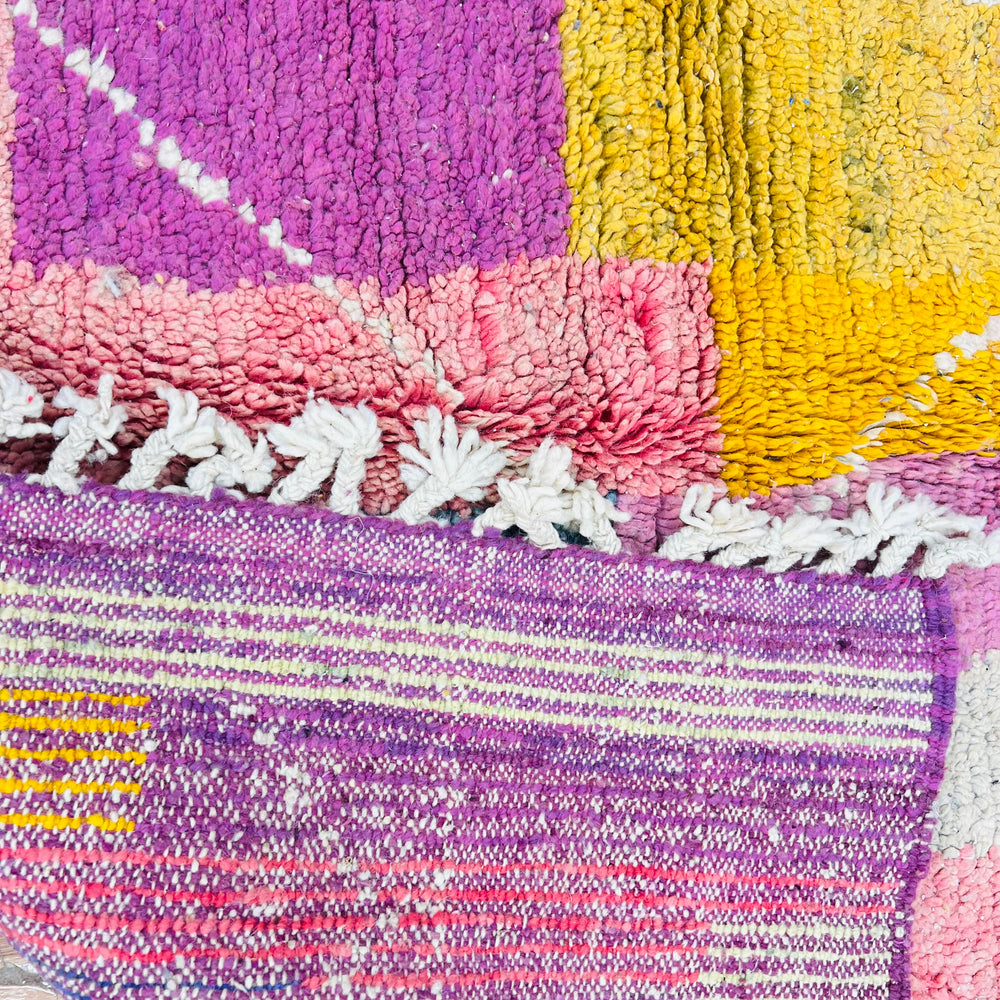 Colorful vintage Moroccan wool rug, featuring geometric patterns in pink, yellow, and purple. Handmade by Berber artisans.