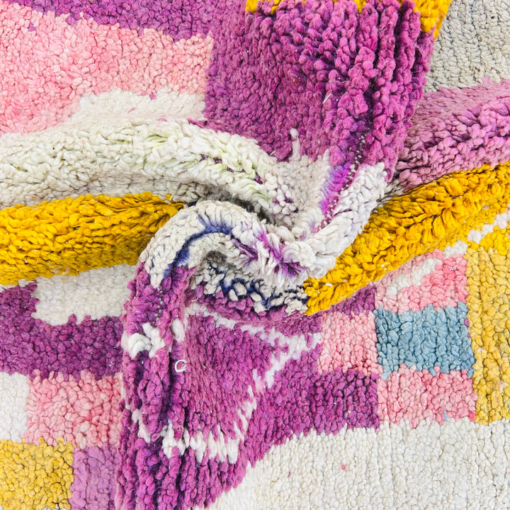 Vibrant vintage Moroccan wool rug in geometric pattern with yellow, pink, and beige tones. Handwoven by Berber artisans.