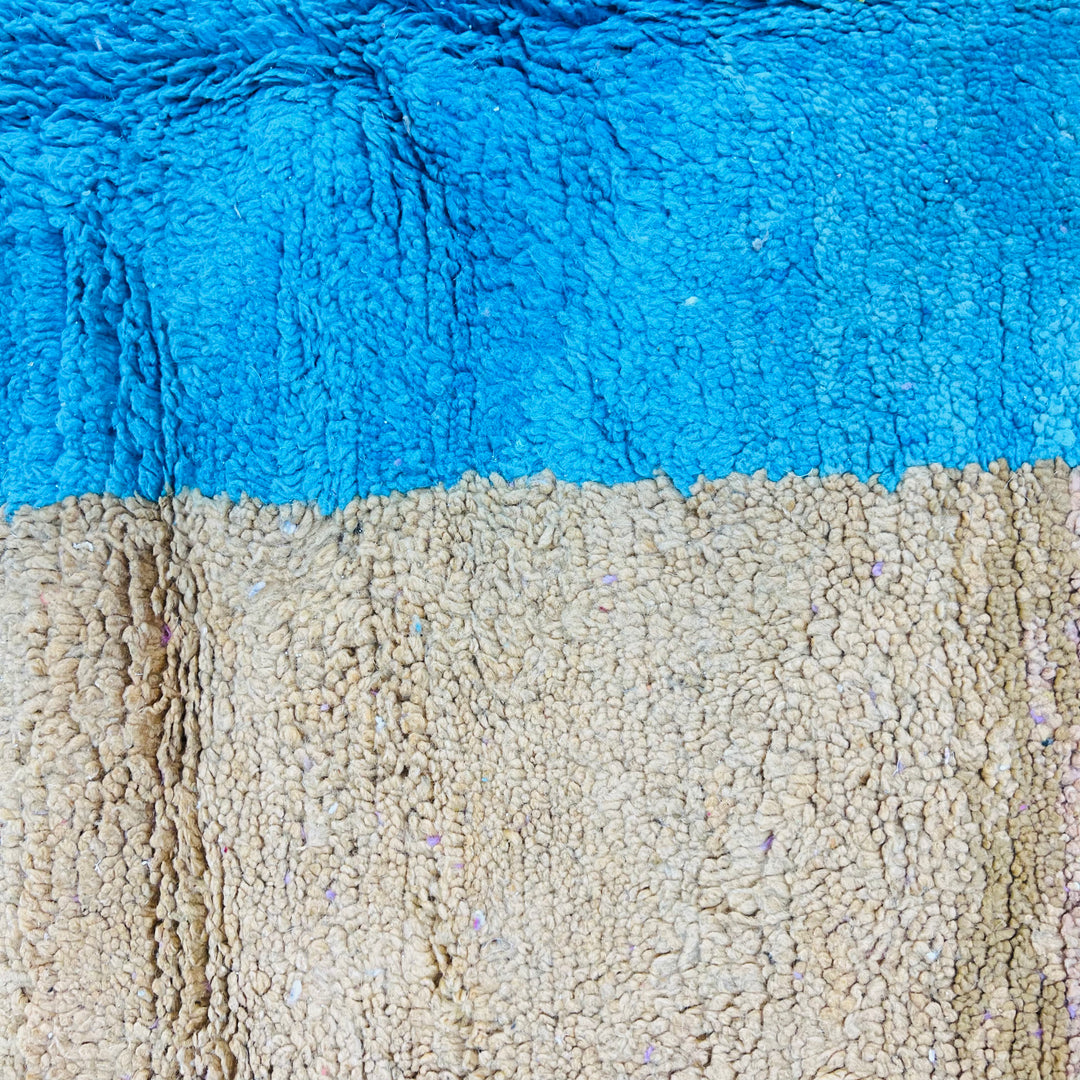 Color block Moroccan wool rug with blue and beige sections, handmade by Berber artisans, showcasing modern design.