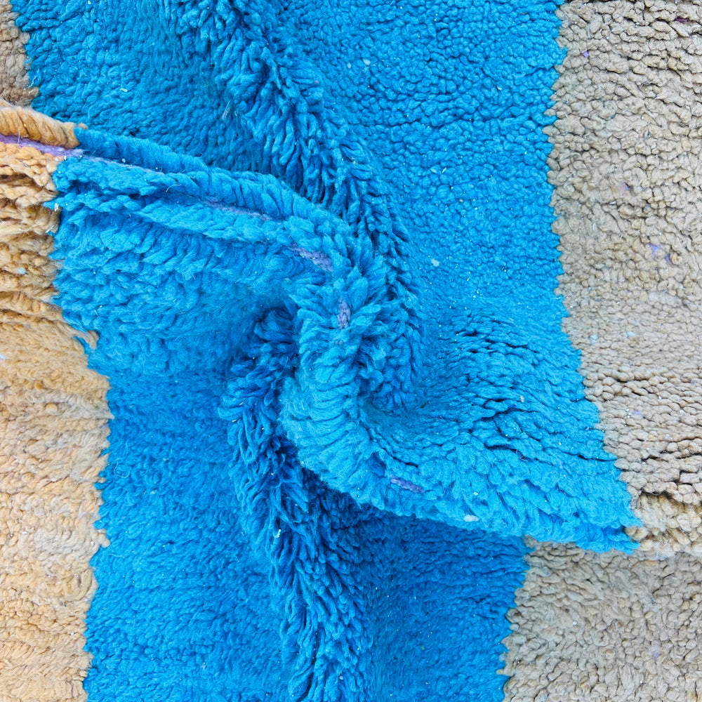 Close-up of vintage Moroccan wool rug in blue, mustard, and beige color block design.