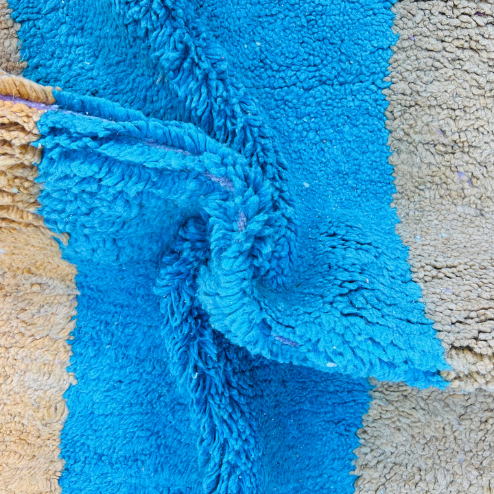 Close-up of vintage Moroccan wool rug in blue, mustard, and beige color block design.
