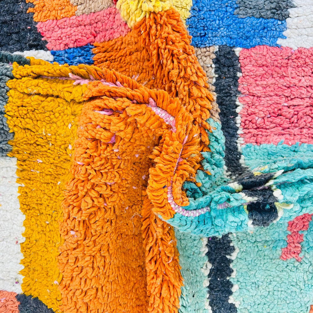 Close-up of colorful geometric vintage Moroccan rug, showcasing vibrant magenta, saffron, pink, and ivory with Berber patterns.