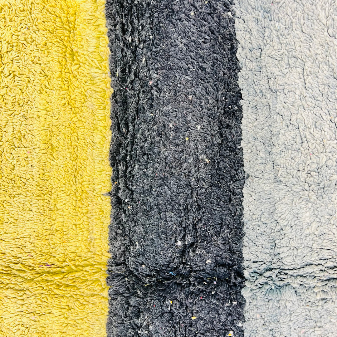 Close-up of vintage Moroccan rug with mustard yellow, black, and soft grey stripes, showcasing traditional Berber craftsmanship.