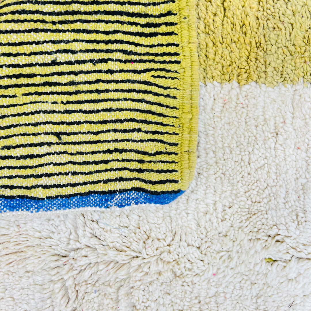 Close-up of a vintage Moroccan wool rug with vibrant yellow, black, and white blocks, showcasing traditional Berber craftsmanship.
