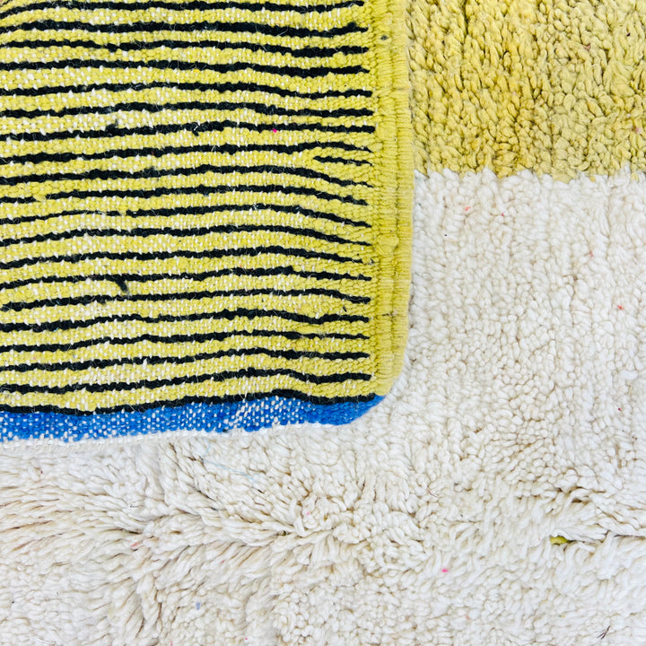 Close-up of a vintage Moroccan wool rug with vibrant yellow, black, and white blocks, showcasing traditional Berber craftsmanship.