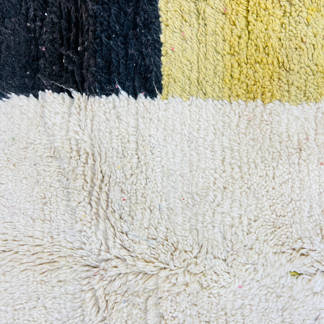 Close-up of a vintage Moroccan Berber rug with mustard, black, and white colors showcasing traditional craftsmanship.