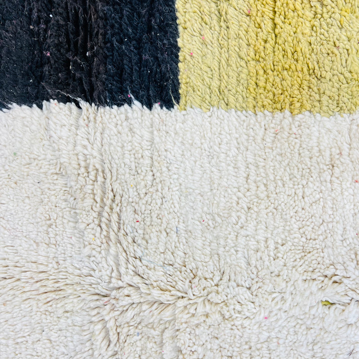 Close-up of a vintage Moroccan Berber rug with mustard, black, and white colors showcasing traditional craftsmanship.