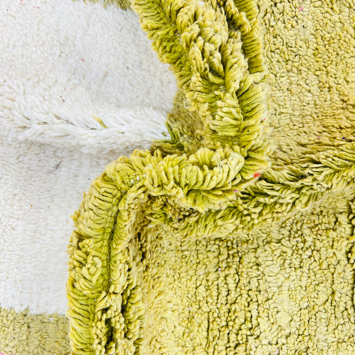 Close-up of a textured, soft green and white vintage Moroccan wool rug with intricate handwoven details.