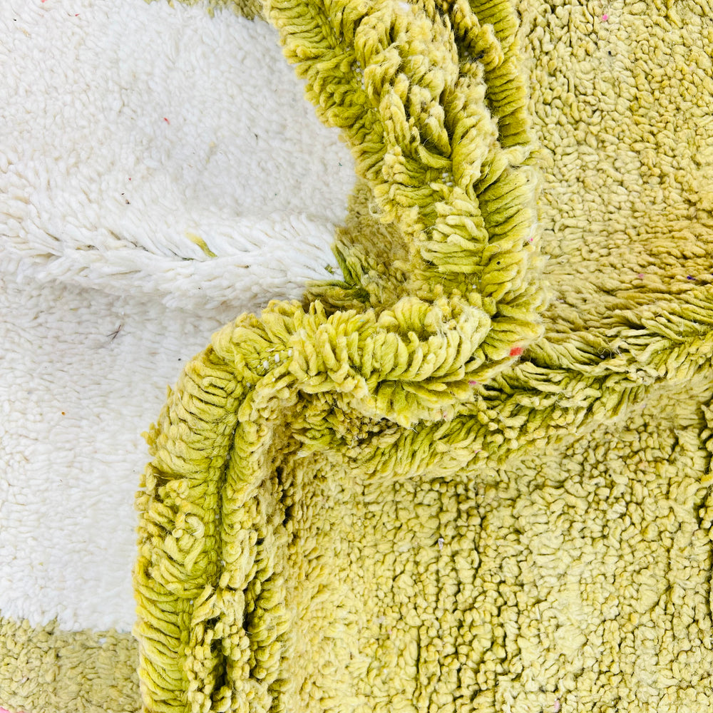Close-up of a textured, soft green and white vintage Moroccan wool rug with intricate handwoven details.