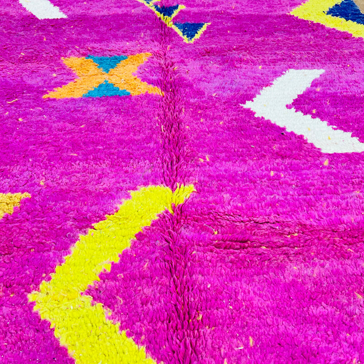 Bold pink Moroccan rug with geometric Berber motifs in yellow, blue, and white, handmade from vintage wool for vibrant decor.