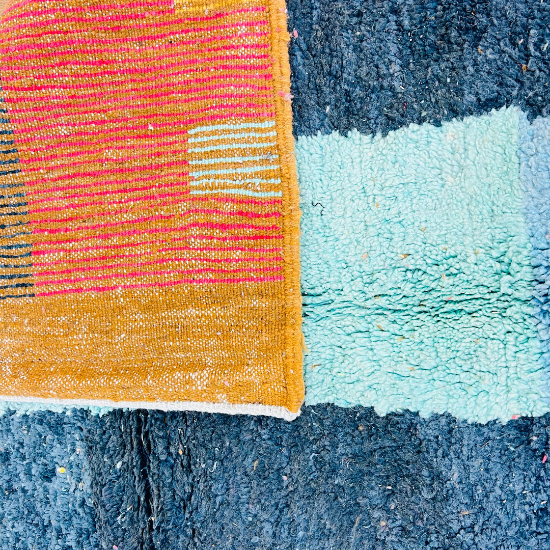 Vintage Moroccan rug with colorful abstract patterns, featuring mustard yellow, pink, turquoise, and grey. Handwoven Berber craftsmanship.