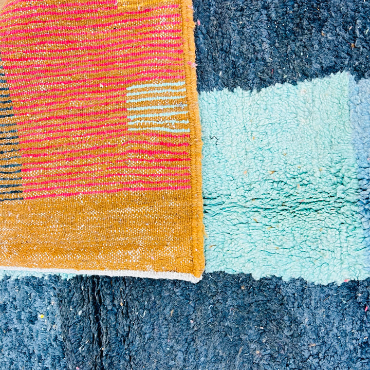 Vintage Moroccan rug with colorful abstract patterns, featuring mustard yellow, pink, turquoise, and grey. Handwoven Berber craftsmanship.