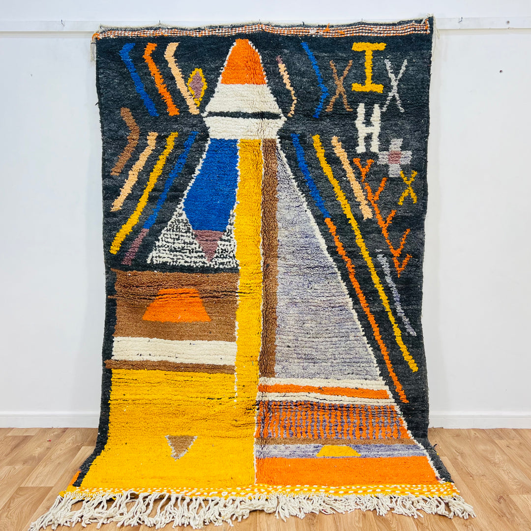 Colorful abstract Moroccan wool rug with geometric and tribal patterns, featuring vivid yellow, orange, and blue designs. Berber craftsmanship.