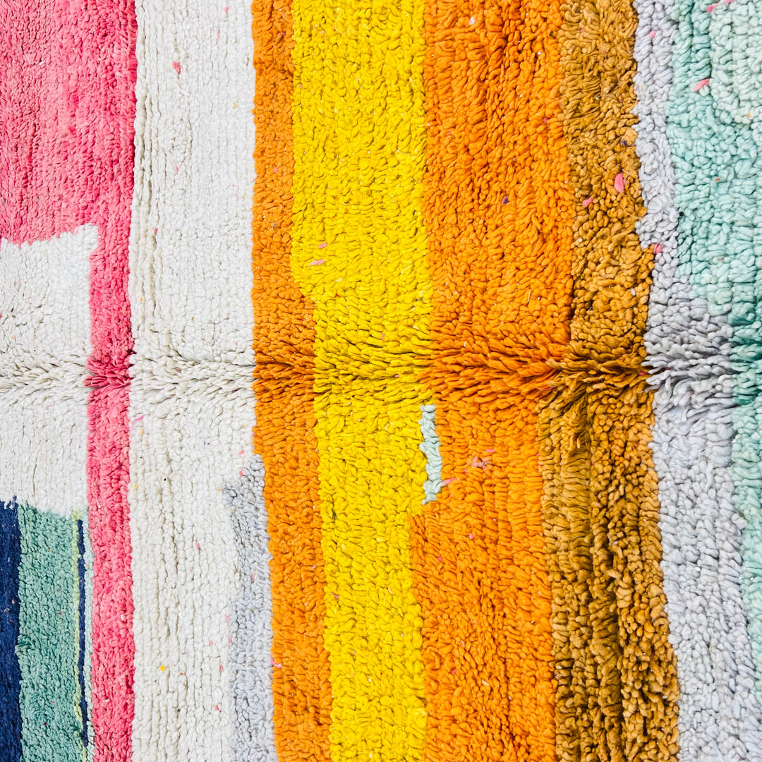Colorful Moroccan wool rug with vibrant stripes in yellow, orange, pink, blue, and white, handwoven in a modern Berber patchwork style.