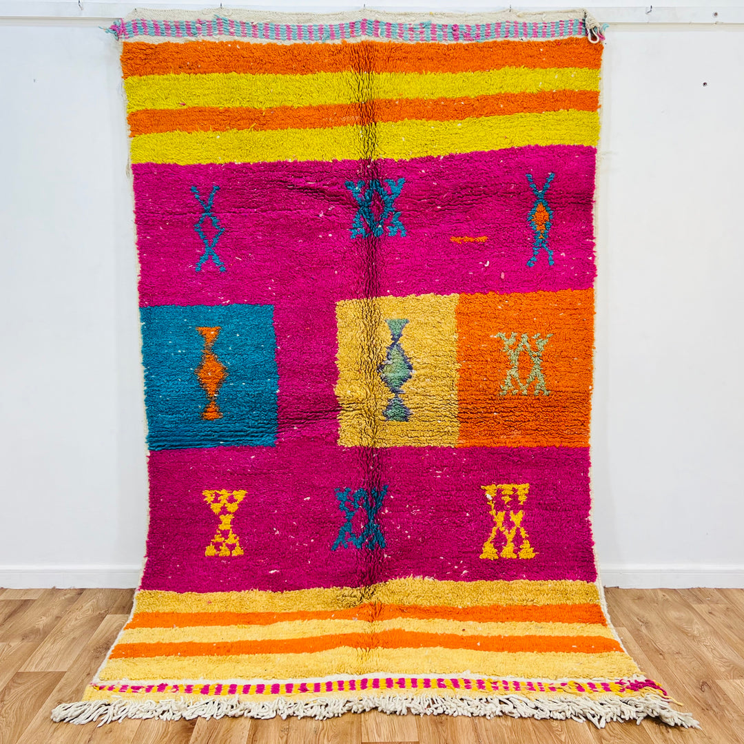 Bold fuchsia vintage Moroccan rug with colorful Berber symbols, tribal hourglass patterns, and border stripes.