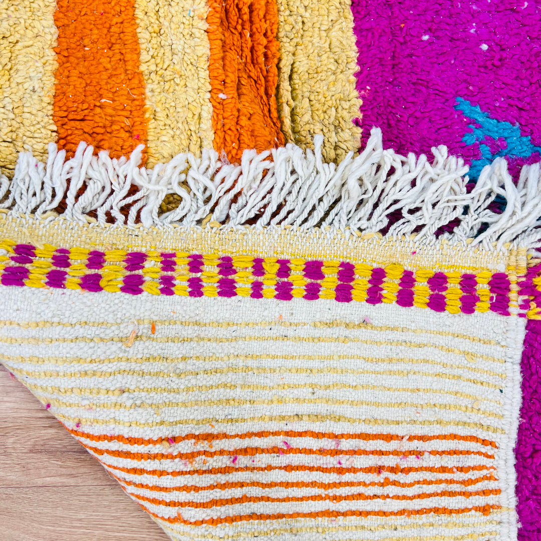 Bold fuchsia vintage Moroccan rug with Berber symbols in yellow, orange, teal, and blue, featuring tribal patterns and fringed edges.