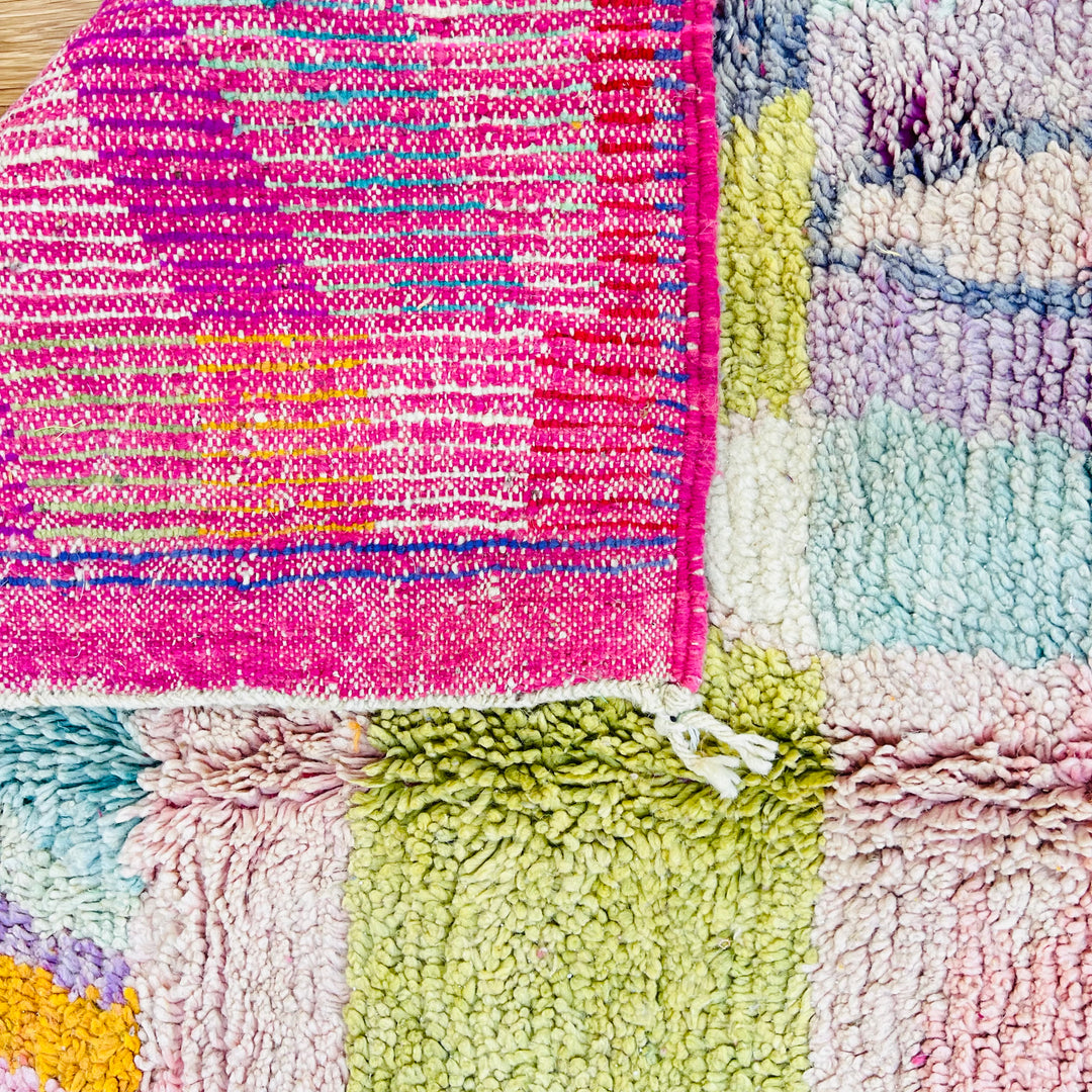 Colorful vintage Moroccan rug with geometric patterns, handwoven with wool in vibrant pink, green, and lilac tones by Berber artisans.