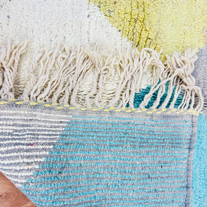 Geometric Earth Tone Moroccan Rug with abstract design and fringe, featuring beige, teal, mustard, and turquoise accents from Morocco.