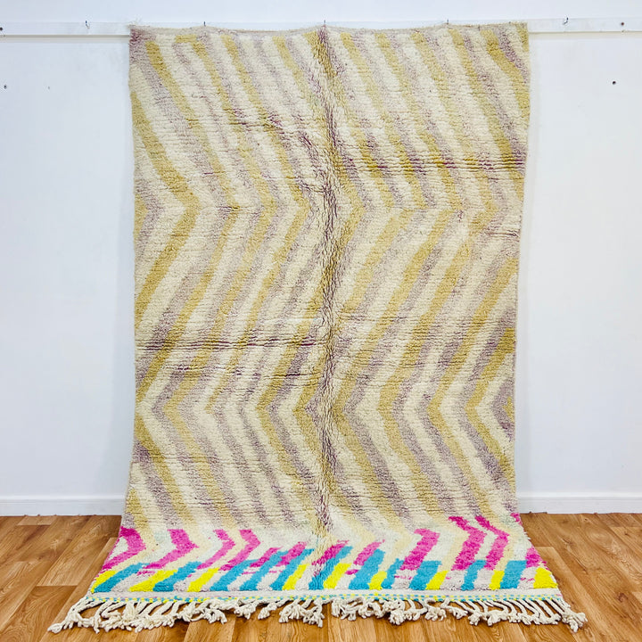 Vintage Moroccan rug with beige chevron pattern and vibrant pink, turquoise accents, 246x162 cm. Handmade cultural heritage piece.
