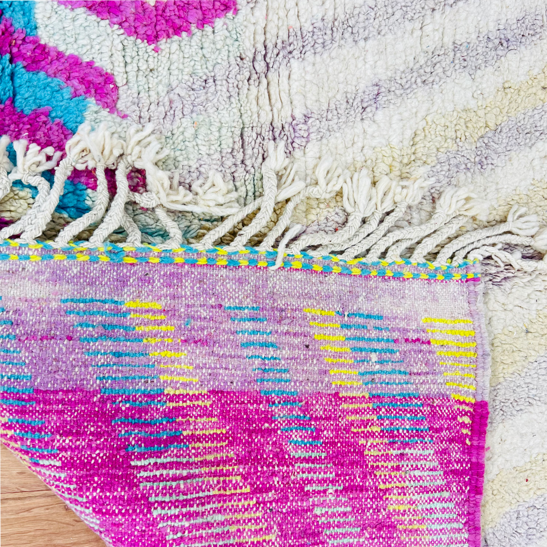 Vibrant vintage Moroccan Berber rug with fuchsia, turquoise, and yellow, showcasing intricate tribal patterns and textured fringes.