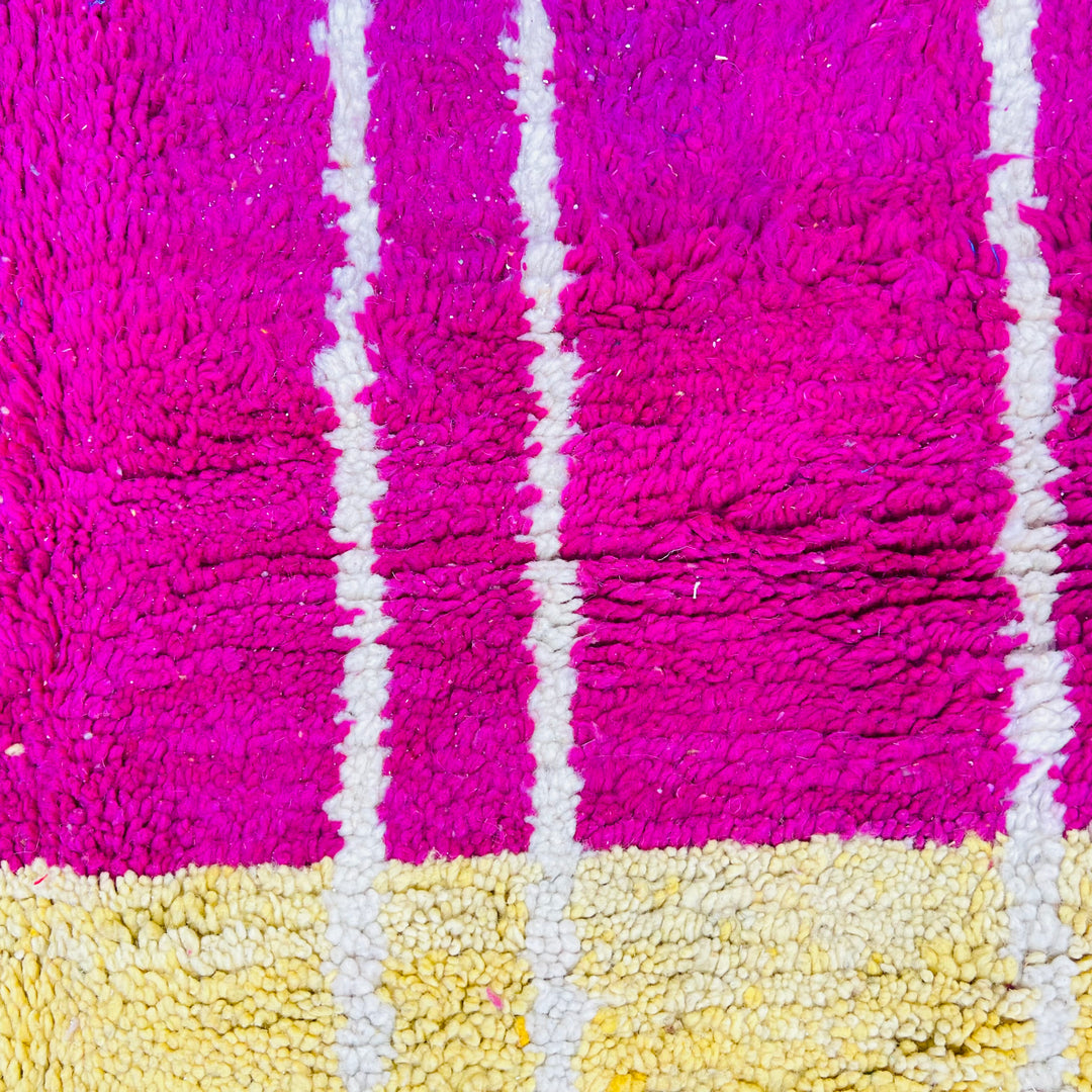 Close-up of colorful Moroccan vintage rug with fuchsia, yellow, and white stripes, showcasing Berber craftsmanship.