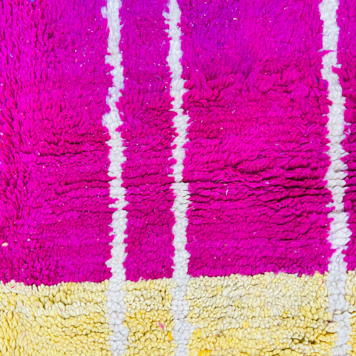 Close-up of colorful Moroccan vintage rug with fuchsia, yellow, and white stripes, showcasing Berber craftsmanship.