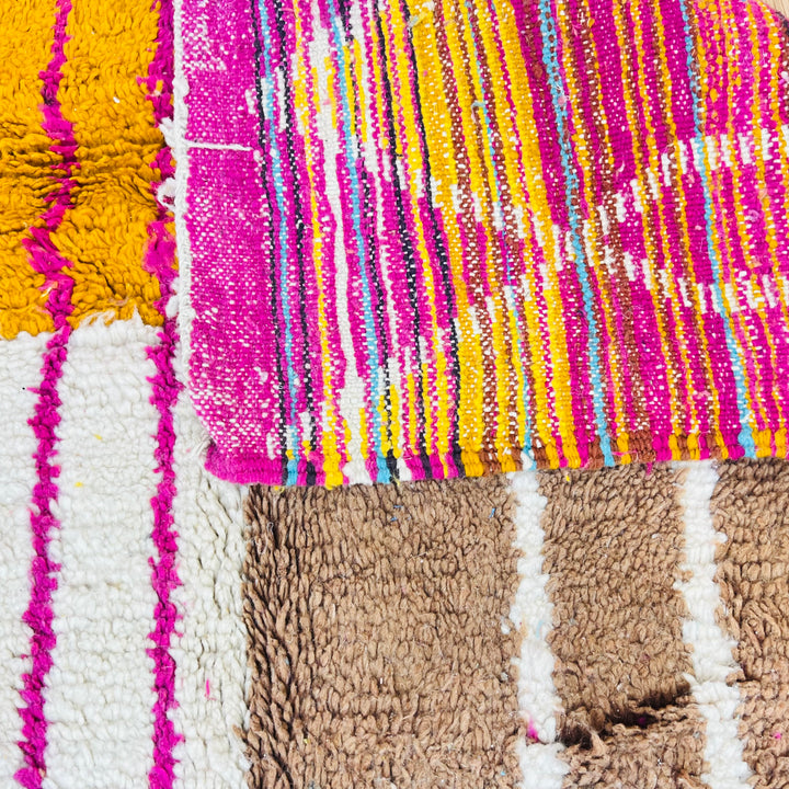 Colorful vintage Moroccan rug close-up featuring fuchsia, orange, turquoise, yellow, and brown tones. Handwoven Berber craftsmanship.
