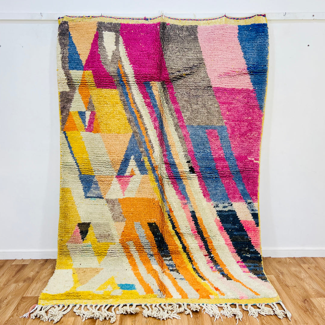 Vintage Moroccan rug with vibrant geometric patterns in pink, orange, blue, and yellow, handcrafted by Berber artisans.
