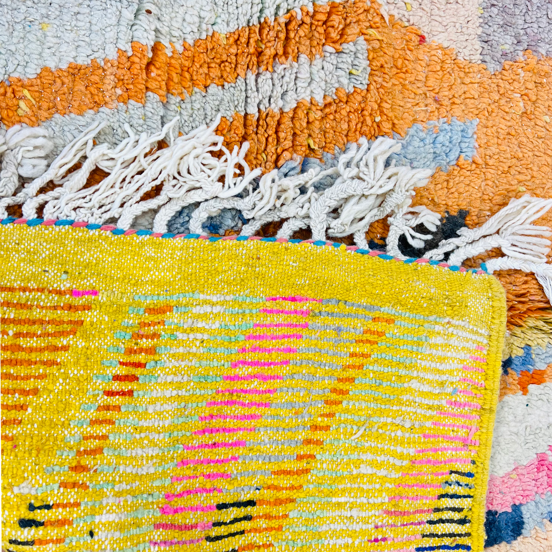 Colorful vintage Moroccan rug with geometric patterns in orange, pink, and yellow, handcrafted by Berber artisans.
