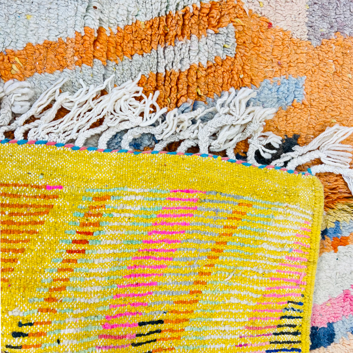 Colorful vintage Moroccan rug with geometric patterns in orange, pink, and yellow, handcrafted by Berber artisans.