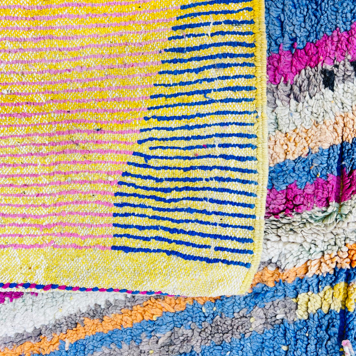 Colorful geometric vintage Moroccan rug featuring yellow, pink, and blue patterns, handcrafted by Berber artisans with wool.