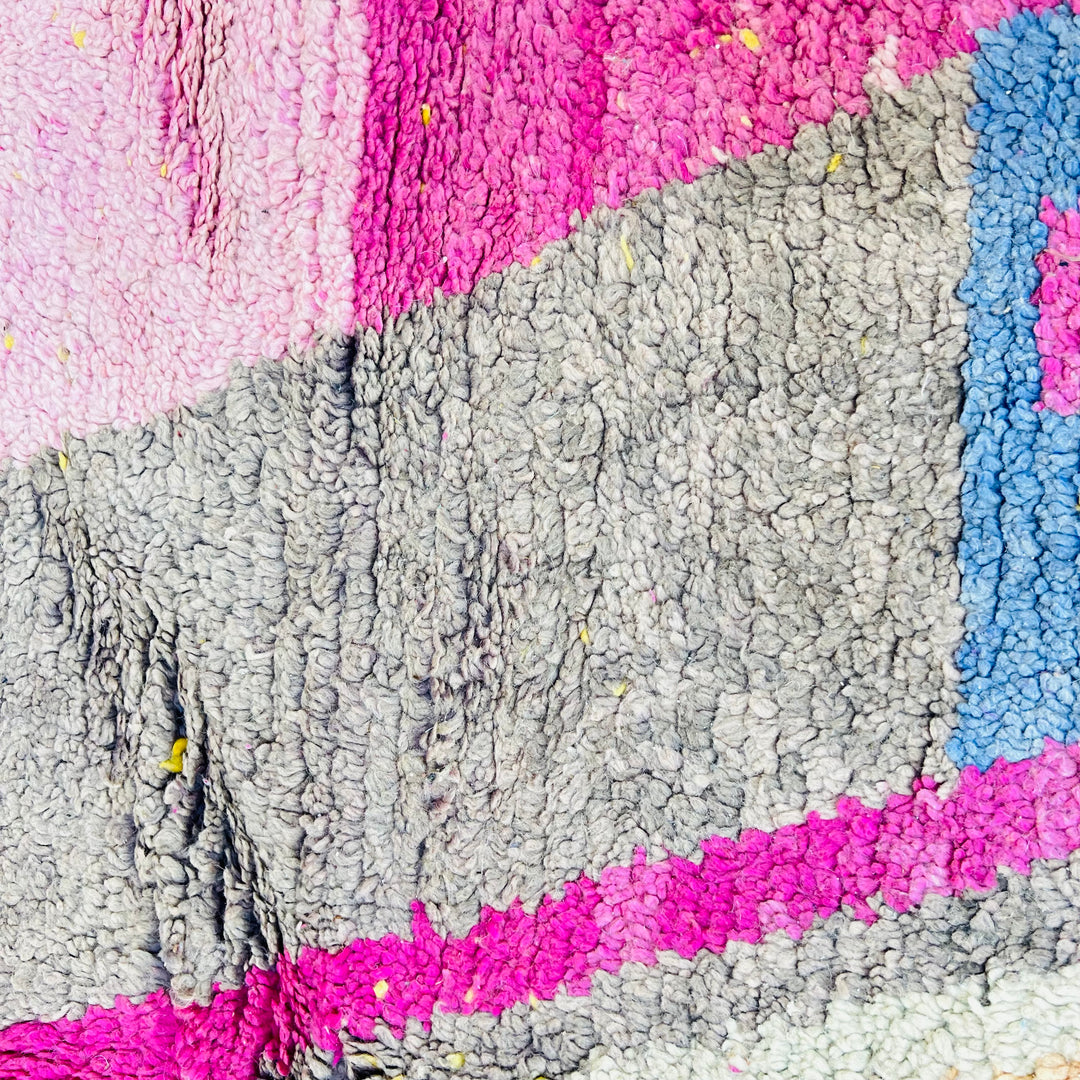 Close-up of a vintage Moroccan rug with vibrant pink, blue, and gray geometric patterns, handcrafted by Berber artisans.