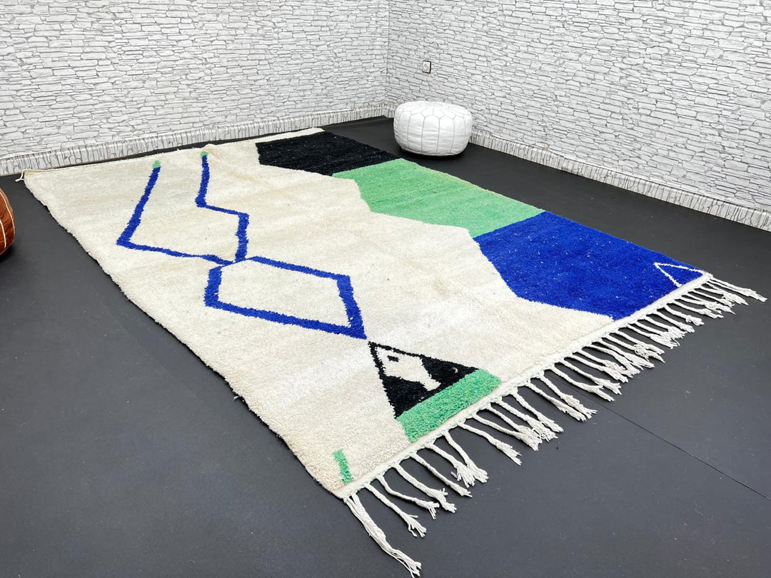 Handmade ivory Moroccan wool rug with green, blue, and black geometric abstract patterns