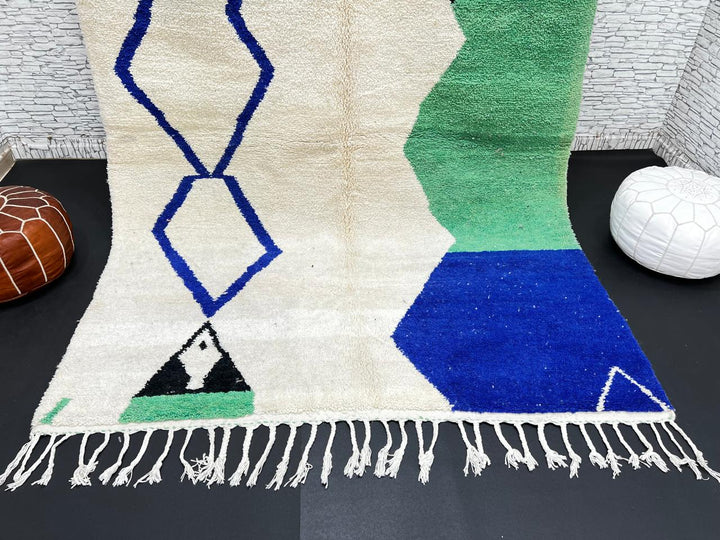 Handmade ivory Moroccan wool rug with green, blue, and black geometric abstract patterns