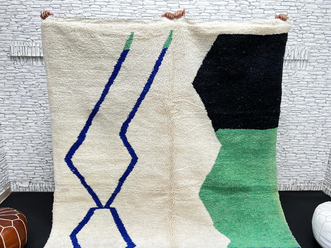 Handmade ivory Moroccan wool rug with green, blue, and black geometric abstract patterns