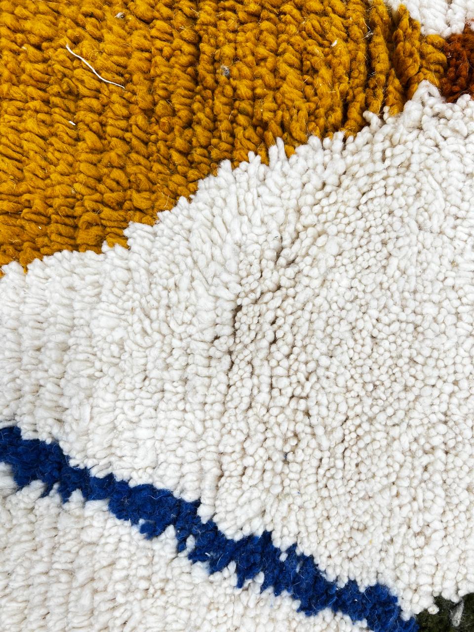 Handwoven ivory Moroccan wool rug with blue, amber, and olive geometric Berber designs