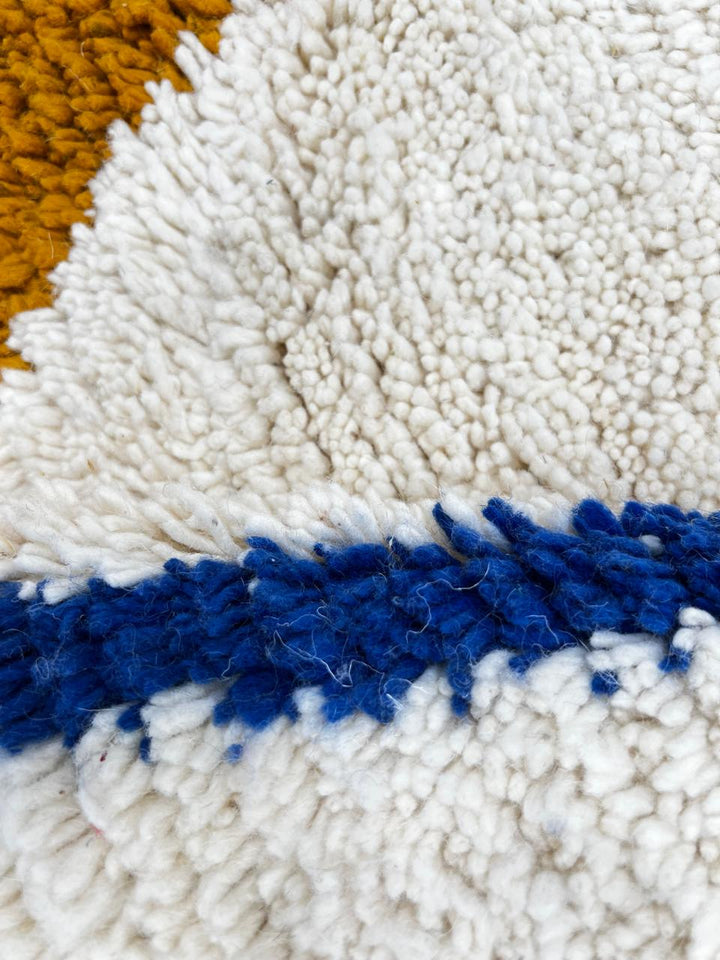 Handwoven ivory Moroccan wool rug with blue, amber, and olive geometric Berber designs