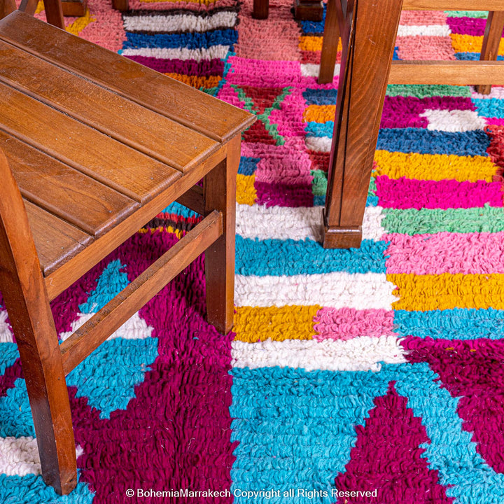 Handmade Moroccan rug with colorful striped and tribal motifs in vibrant wool