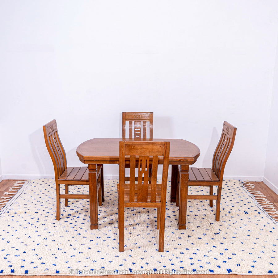 Large white Moroccan rug with blue dots under wooden dining table and chairs, showcasing Beni Ourain craftsmanship.