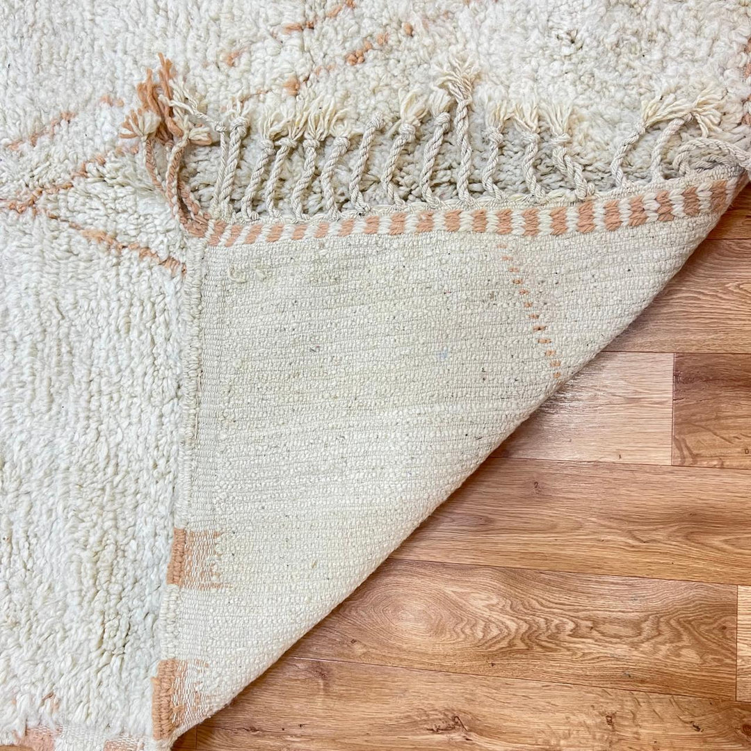 Handmade Moroccan wool runner rug in cream with subtle peach geometric lines and fringed end