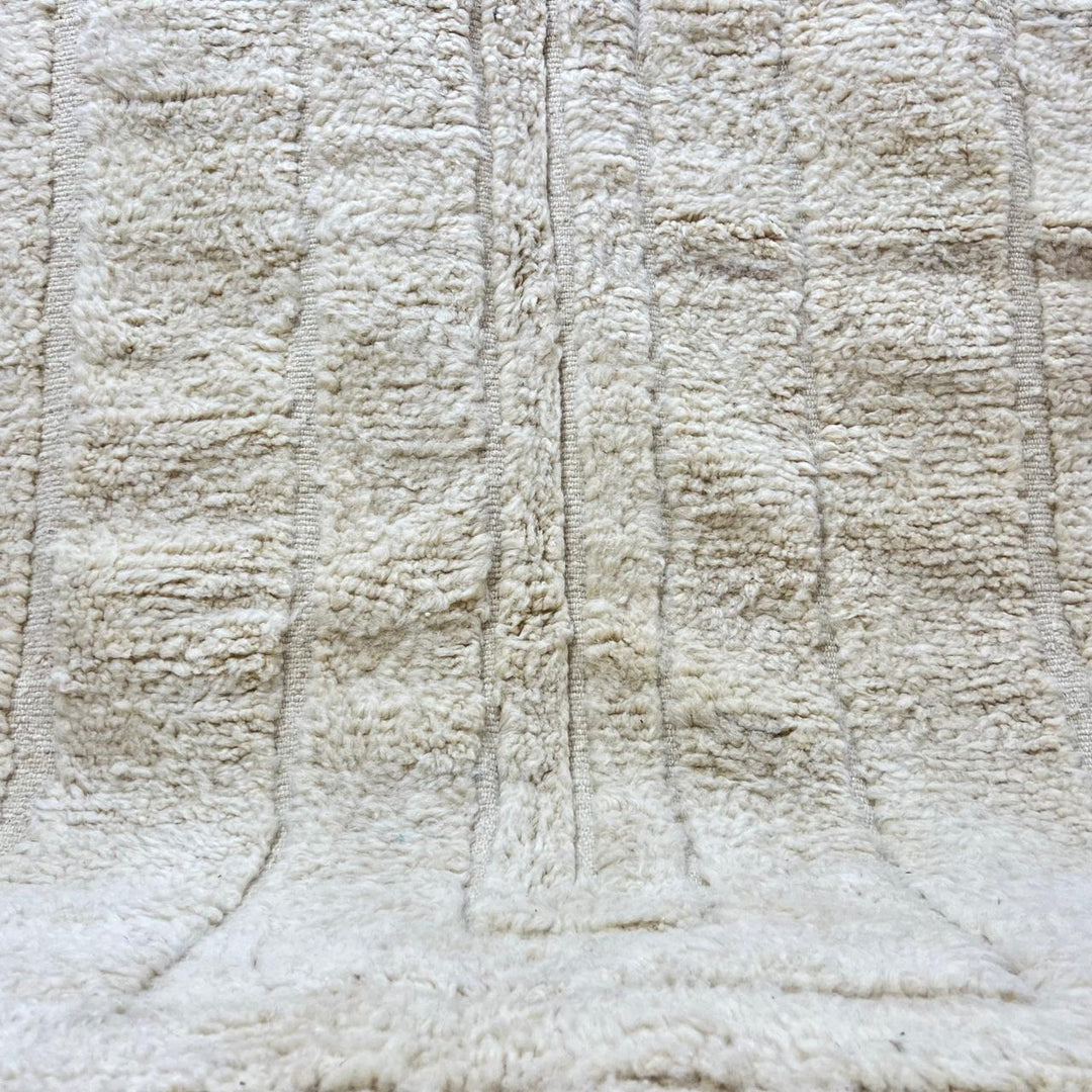 Round cream handmade Moroccan wool rug with carved minimalist geometric design on white background