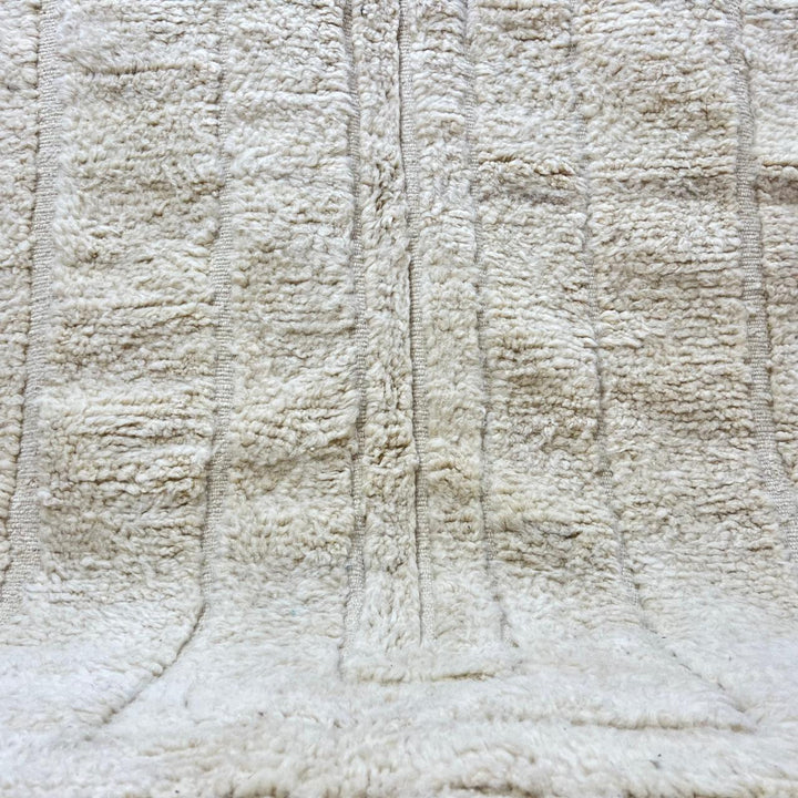 Round cream handmade Moroccan wool rug with carved minimalist geometric design on white background