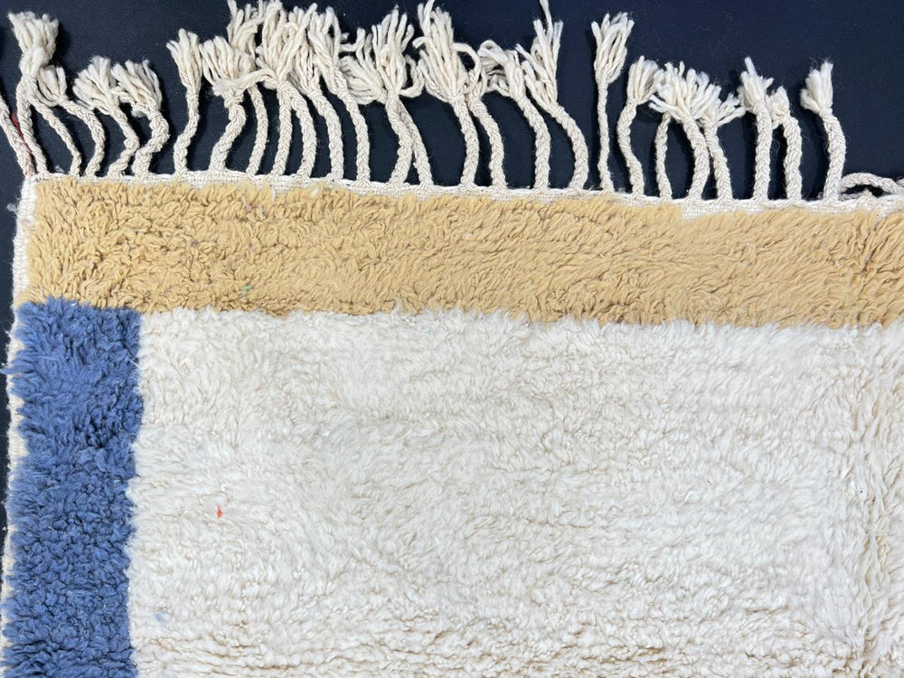 Handmade Moroccan runner rug with white wool center, blue borders, and beige accents, crafted by Berber artisans.