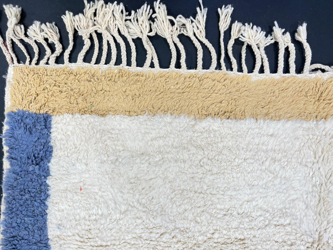Handmade Moroccan runner rug with white wool center, blue borders, and beige accents, crafted by Berber artisans.