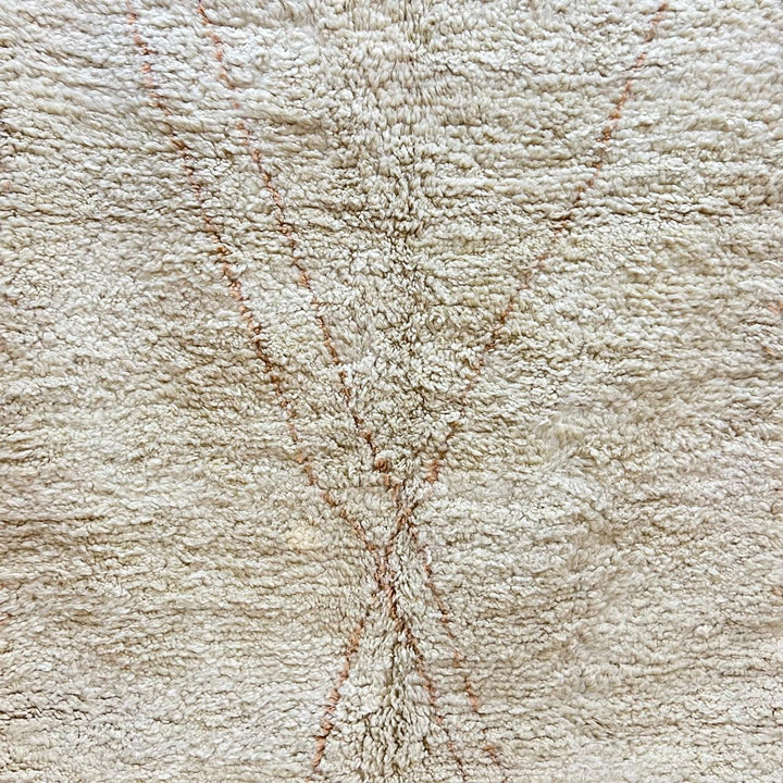 Close-up of a plush creamy beige Moroccan Beni Mrirt rug, handcrafted from soft natural wool, featuring a subtle X-shaped design.