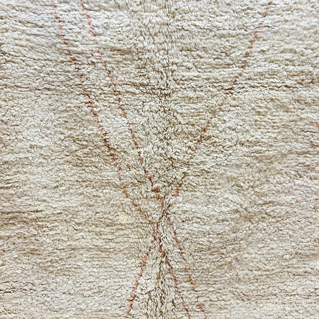 Close-up of a plush creamy beige Moroccan Beni Mrirt rug, handcrafted from soft natural wool, featuring a subtle X-shaped design.