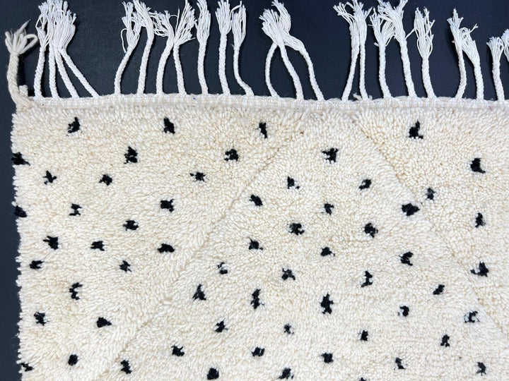 Handmade Moroccan runner rug with black dotted tuft pattern and soft geometric diamond outlines on a white wool background.